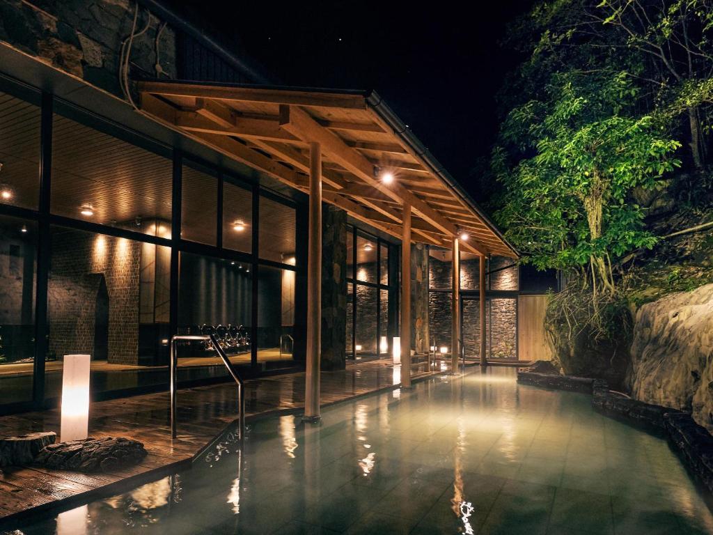 une maison avec une piscine devant elle la nuit dans l'établissement Ooedo Onsen Monogatari Premium Shirahama Gyoen, à Shirahama