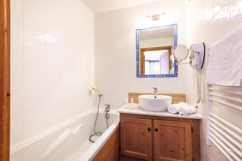une salle de bain avec un lavabo, une baignoire et un miroir dans l'établissement Chalet des Neiges Plein Sud, à Val Thorens