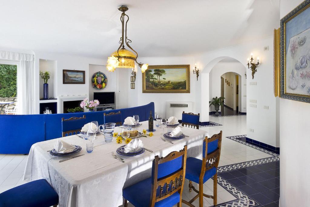 une salle à manger avec une table blanche et des chaises bleues dans l'établissement Villa Felicita, à Massa Lubrense