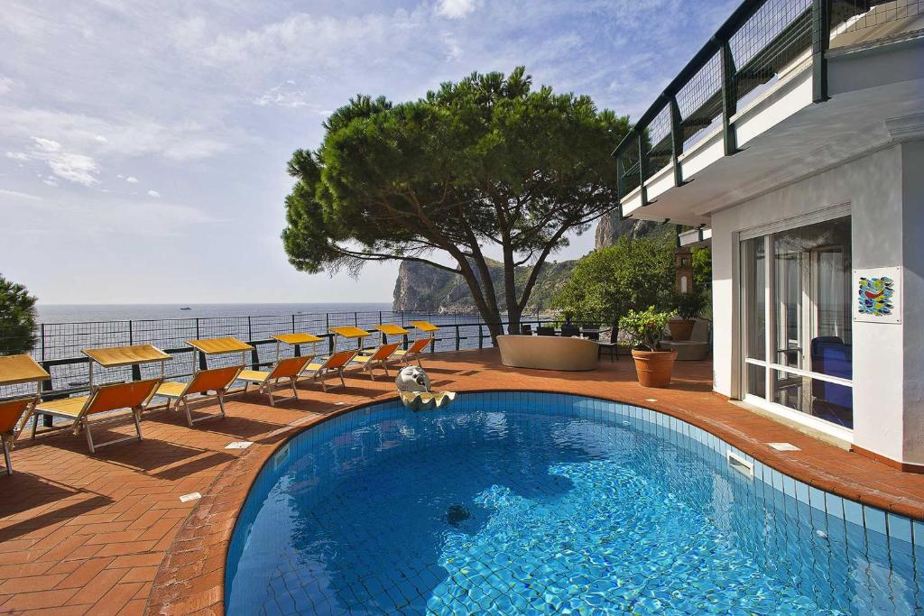 une piscine avec des chaises et l'océan en arrière-plan dans l'établissement Villa Felicita, à Massa Lubrense