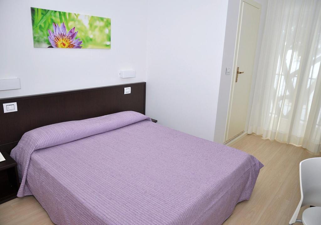 une chambre avec un lit violet avec une couverture violette dans l'établissement Hotel Lugano, à Riccione