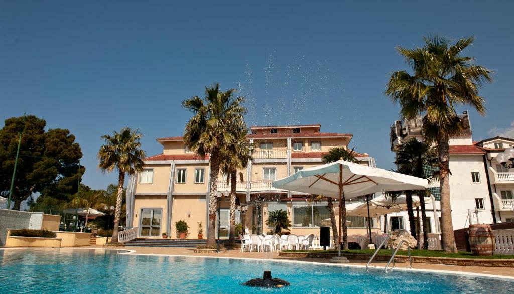 une piscine avec un parasol et un bâtiment dans l'établissement Park Hotel Tyrrenian, à Amantea