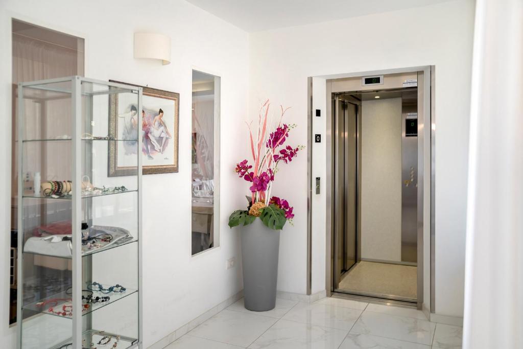 un couloir avec un vase de fleurs sur un mur dans l'établissement Hotel Tre Rose, à Caorle