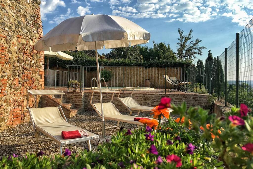 une terrasse avec 2 chaises et une table avec un parasol dans l'établissement Pasqui Villas La Capanna accogliente casa in paese con vista piscina WiFi, à San Giovanni dʼAsso