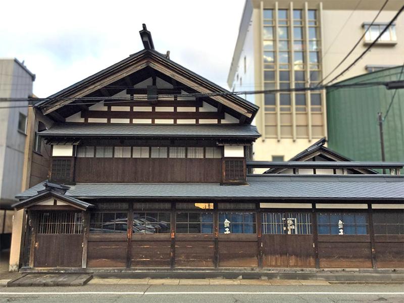 un bâtiment en bois avec une porte dans une ville dans l'établissement Ohmachiso, à Akita