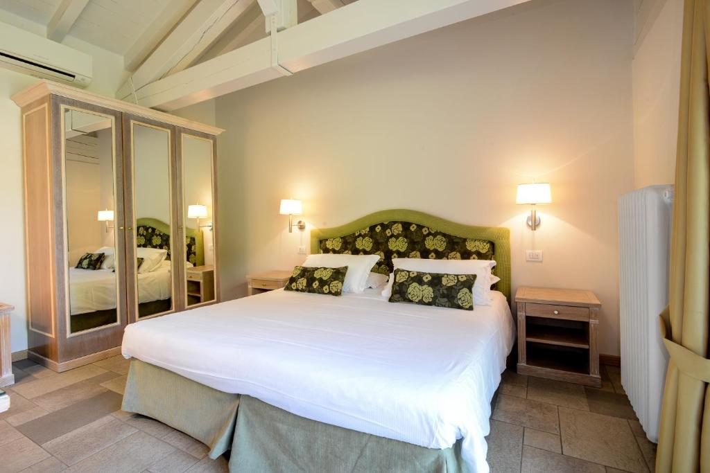 une chambre avec un grand lit avec des draps et des oreillers blancs dans l'établissement Residence Ortensia, à Baveno