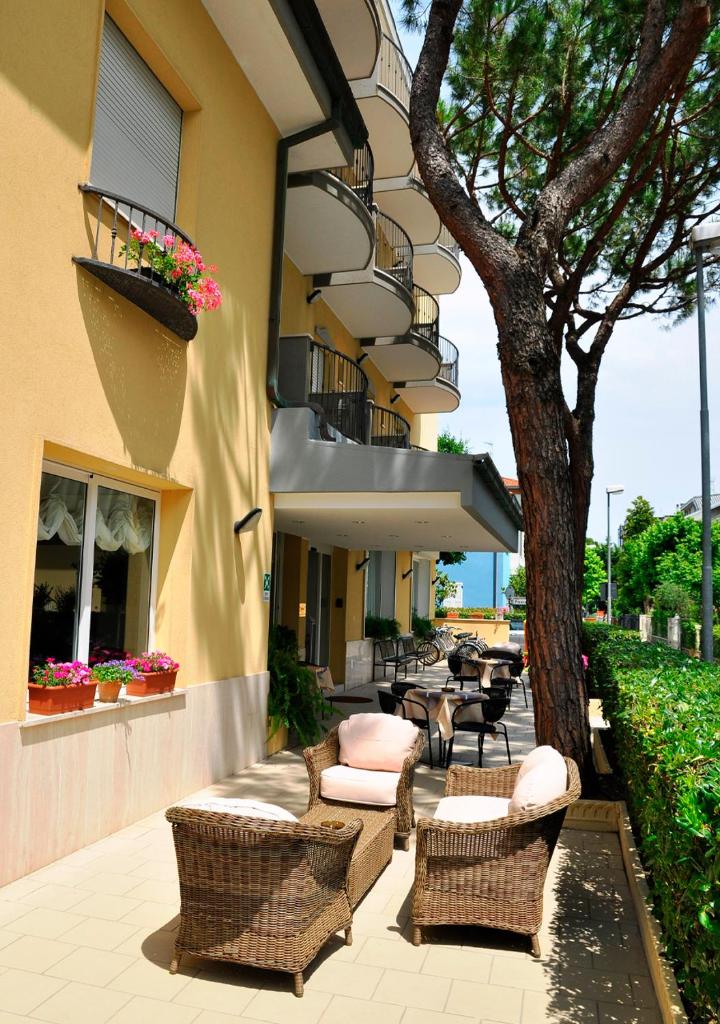 un patio avec des chaises et un arbre à côté d'un bâtiment dans l'établissement Hotel Lugano, à Riccione