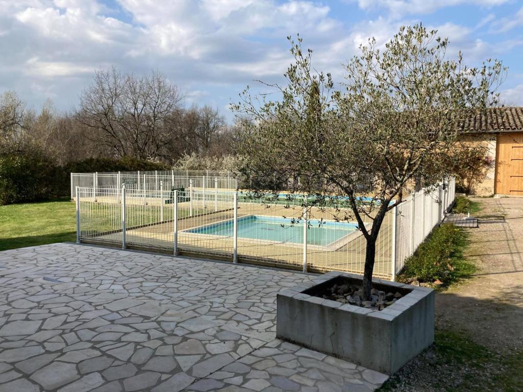 une clôture avec un arbre à côté d'une piscine dans l'établissement Camping Fargogne, à Puygaillard-de-Quercy 9 autres photos