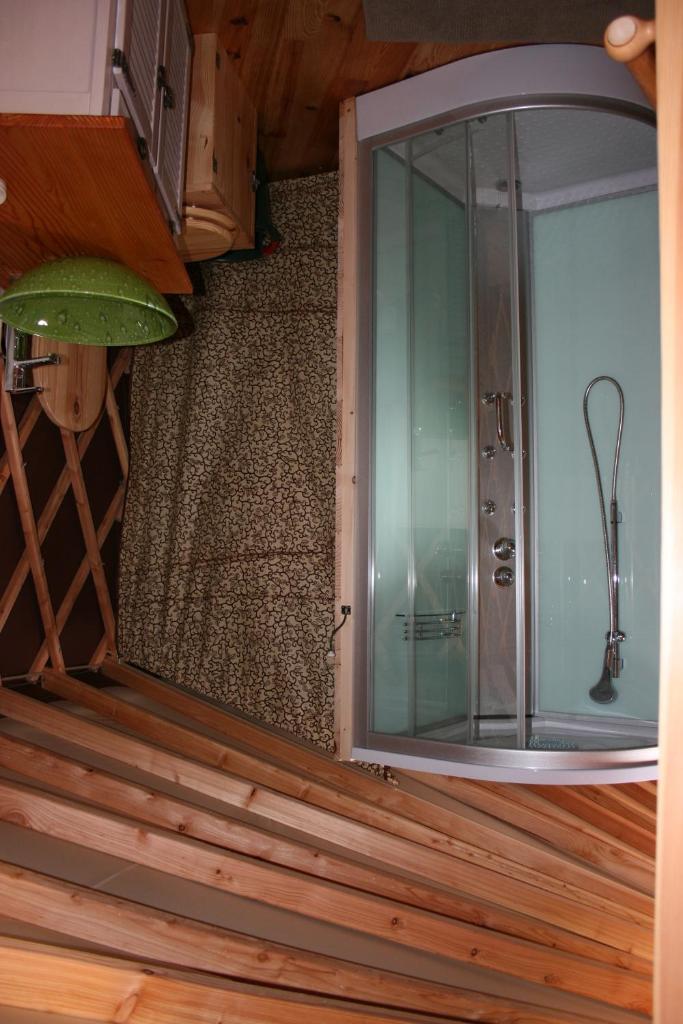 Cette chambre dispose de parquet et d'une douche en verre. dans l'établissement Yourtes en Terrasse, à Bonneval