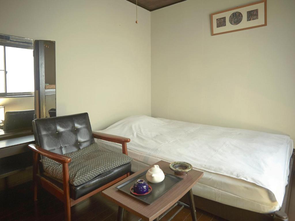 une chambre avec un lit, une chaise et une table dans l'établissement Takeyaso Ryokan, à Amagasaki