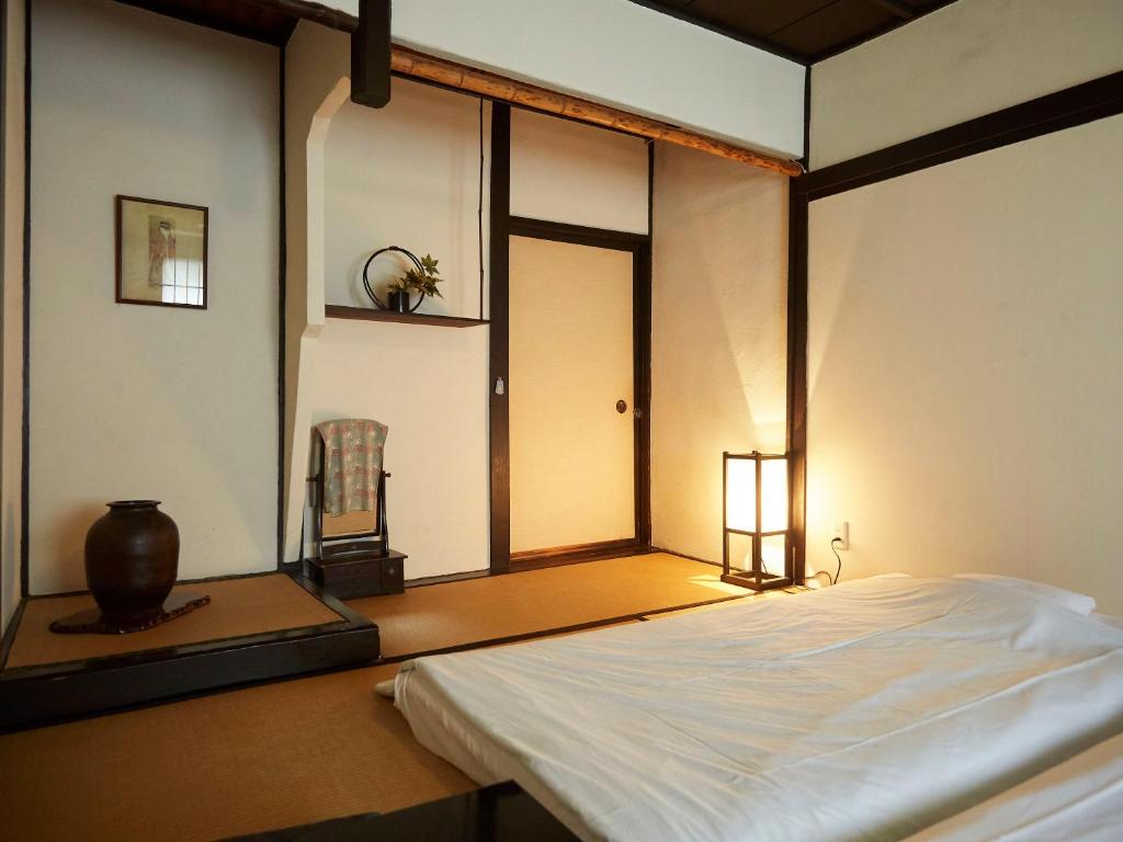 une chambre avec un lit blanc avec une fenêtre dans l'établissement Takeyaso Ryokan, à Amagasaki