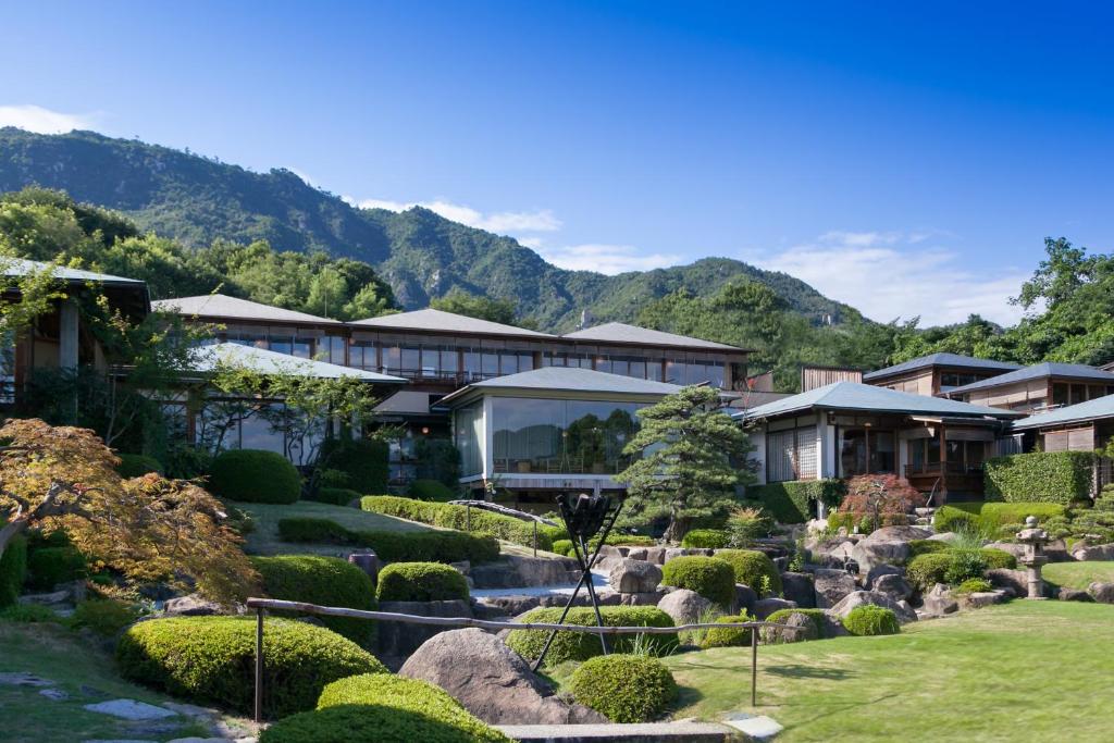 un complexe avec un jardin et des montagnes en arrière-plan dans l'établissement Sekitei, à Hatsukaichi