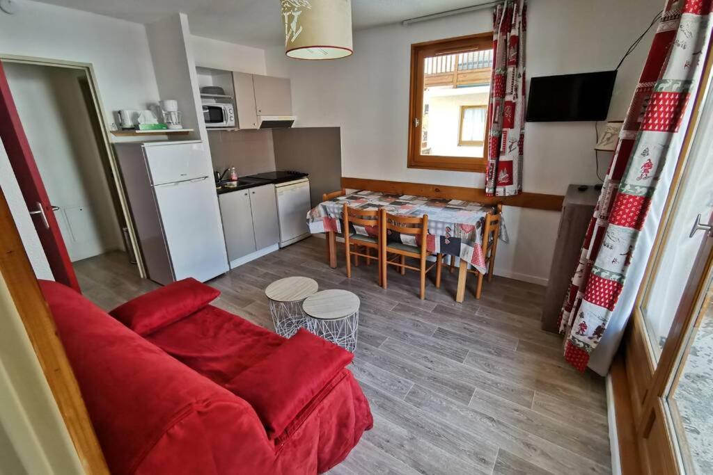un salon avec un canapé rouge et une cuisine dans l'établissement Logement 4/6 personnes à la montagne avec piscine, à Saint-Sorlin-dʼArves