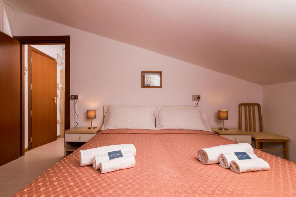 une chambre avec un grand lit avec deux serviettes dessus dans l'établissement Hotel Lydia, à Cervia