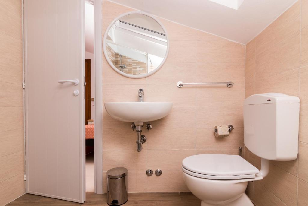 une salle de bain avec toilettes, lavabo et miroir dans l'établissement Hotel Lydia, à Cervia
