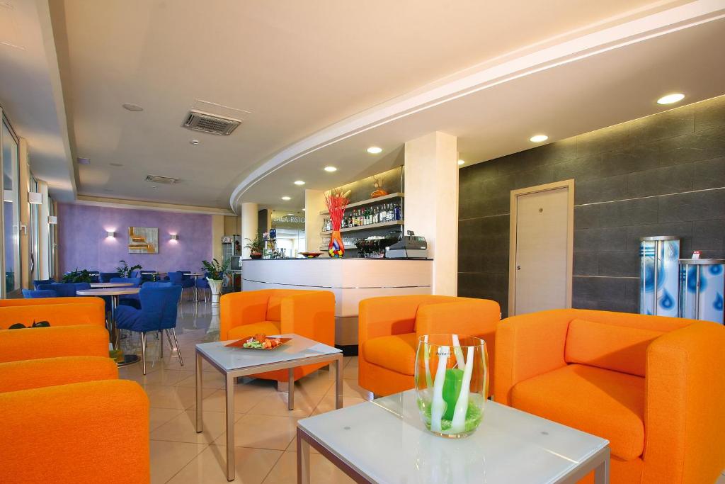 un restaurant avec des chaises et des tables orange et un bar dans l'établissement Hotel Bologna, à Lignano Sabbiadoro