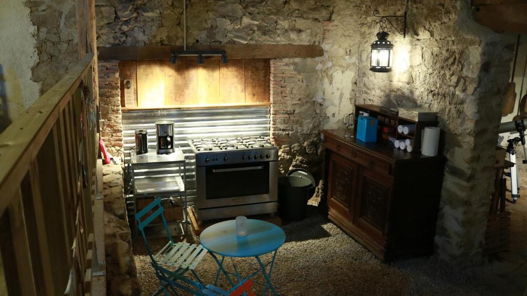 une cuisine avec une cuisinière et un comptoir avec un tabouret dans l'établissement La Toile sous Les Étoiles, à Charron