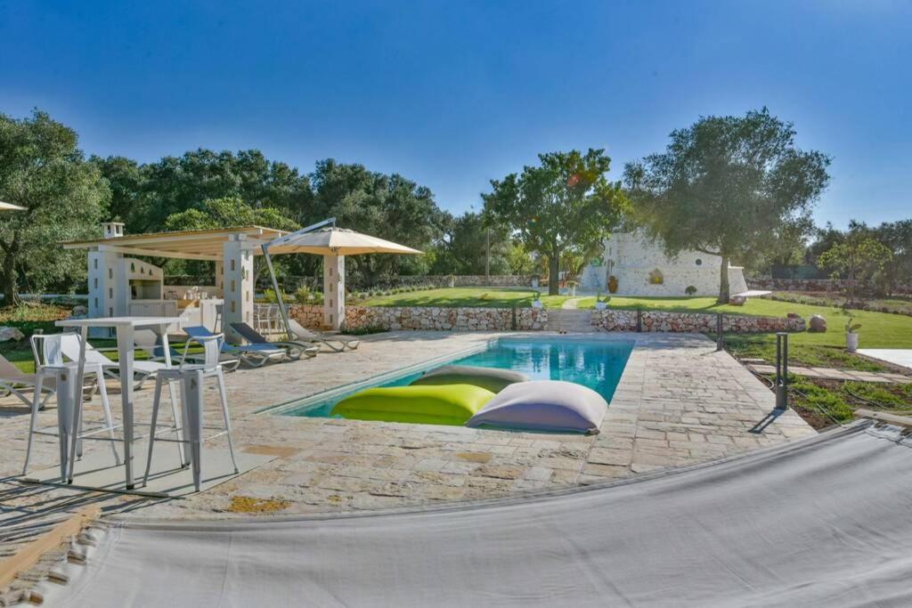- une piscine avec une table et des chaises dans la cour dans l'établissement Tenuta Trullo Pietra Bianca, à Ostuni