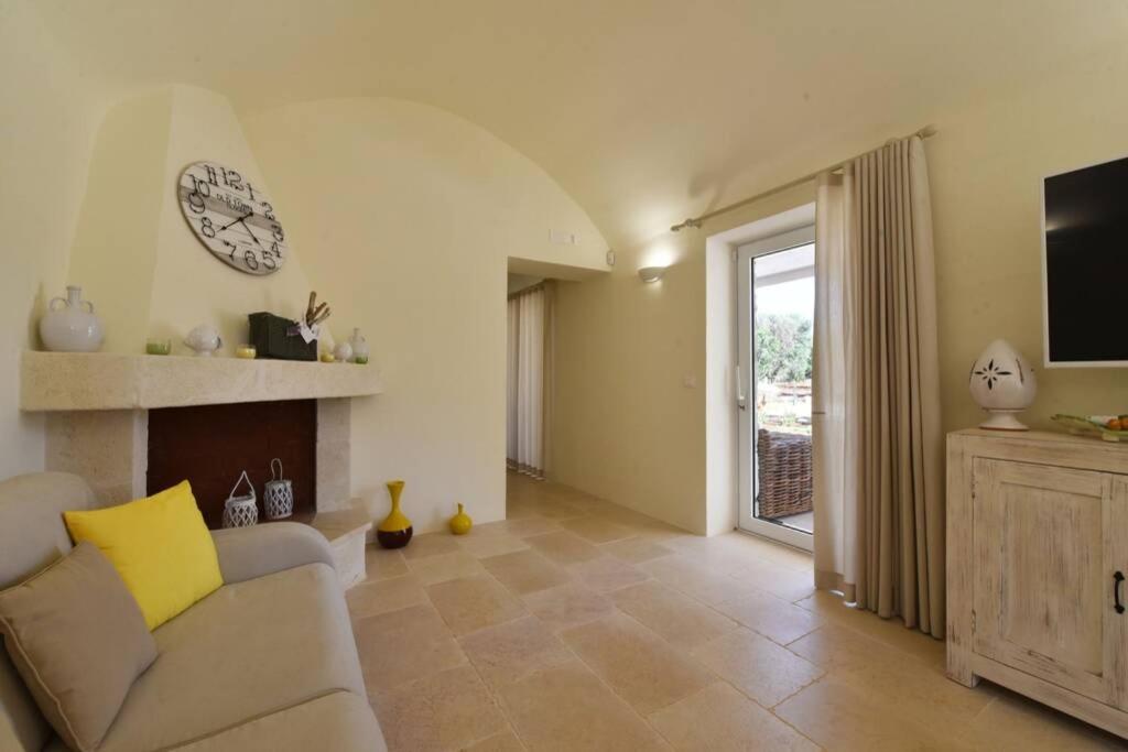 un salon avec un canapé et une horloge au mur dans l'établissement Tenuta Trullo Pietra Bianca, à Ostuni