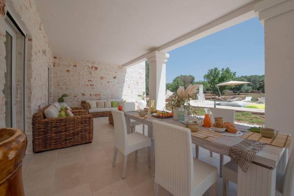 une salle à manger avec une table et des chaises et un salon dans l'établissement Tenuta Trullo Pietra Bianca, à Ostuni