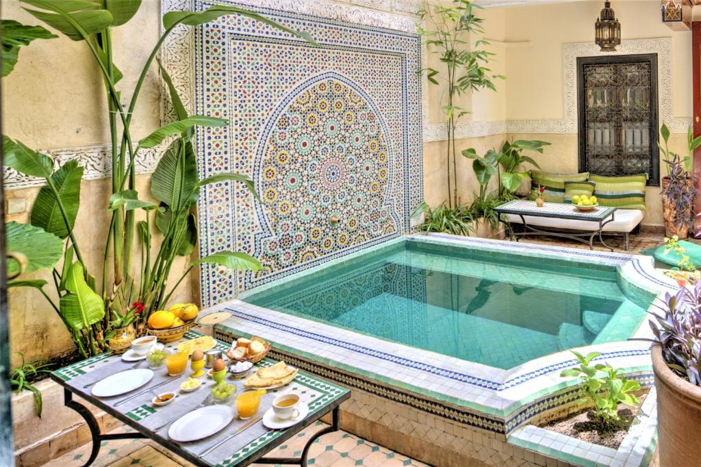 - une piscine dans un jardin avec une table et de la nourriture dans l'établissement Riad Dar El Souk, à Marrakech