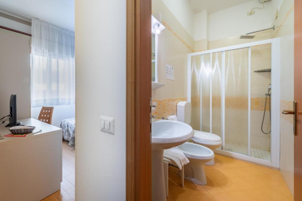 une salle de bain avec un lavabo, des toilettes et une douche dans l'établissement Hotel Del Corso, à Bibione