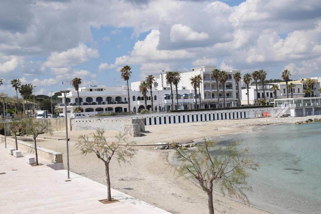 une plage avec des palmiers et un bâtiment blanc dans l'établissement Hotel Profumo Di Mare, à Otrante