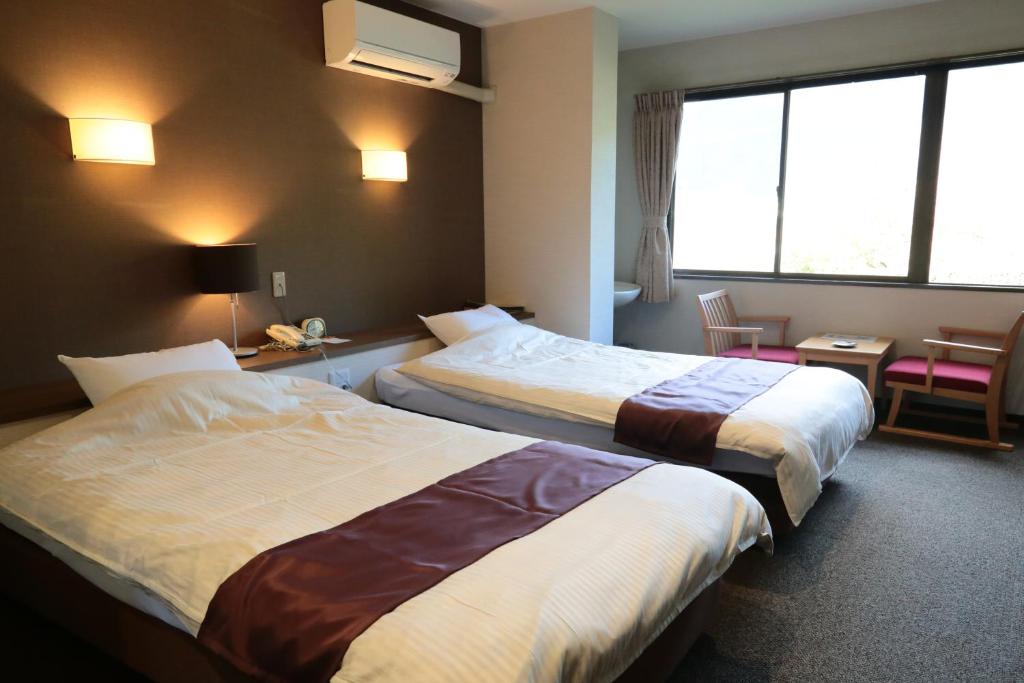 une chambre d'hôtel avec deux lits et une fenêtre dans l'établissement Iruka Onsen Hotel Seiryuusou, à Kumano