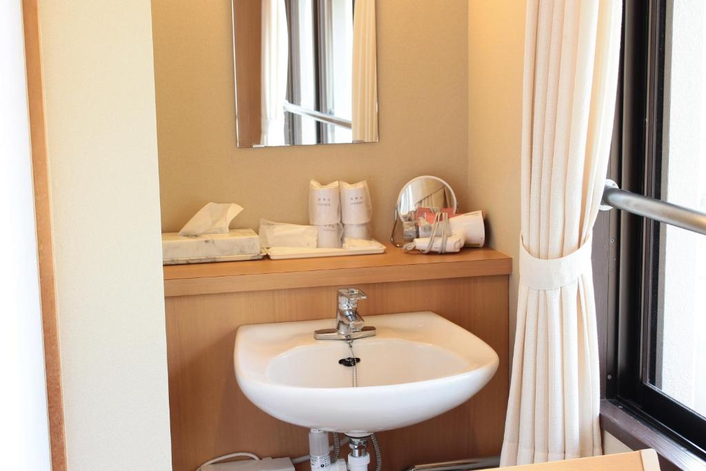 une salle de bain avec un lavabo et un miroir dans l'établissement Iruka Onsen Hotel Seiryuusou, à Kumano