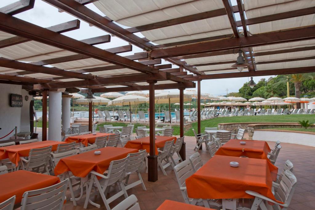 un patio extérieur avec des tables orange et des chaises blanches dans l'établissement Hotel Cala di Mola, à Porto Azzurro