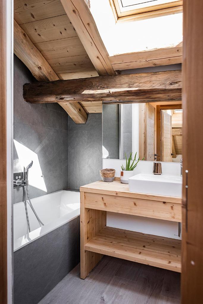 La salle de bains est pourvue d'une baignoire blanche, d'un lavabo et d'une baignoire. dans l'établissement Nouveau et spacieux, Place de l'Eglise et terrasse privative, à La Clusaz