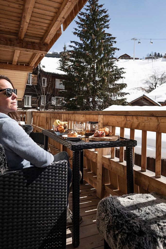 une femme assise à une table sur un pont dans l'établissement Spacieux duplex avec vue, à La Clusaz