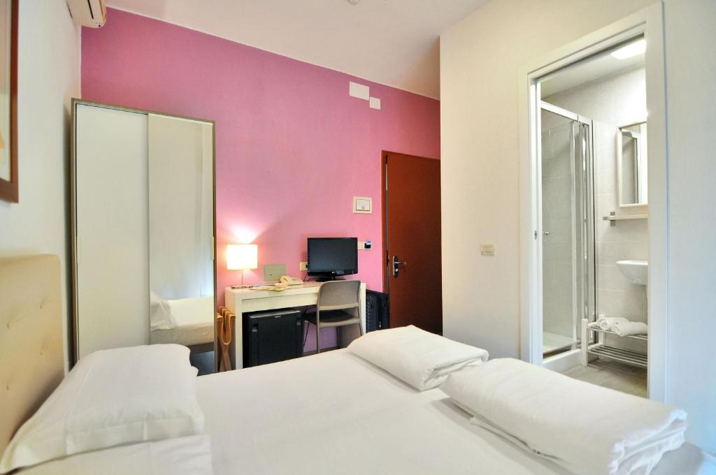 une chambre avec deux lits et un mur rose dans l'établissement Hotel Nederland, à Caorle