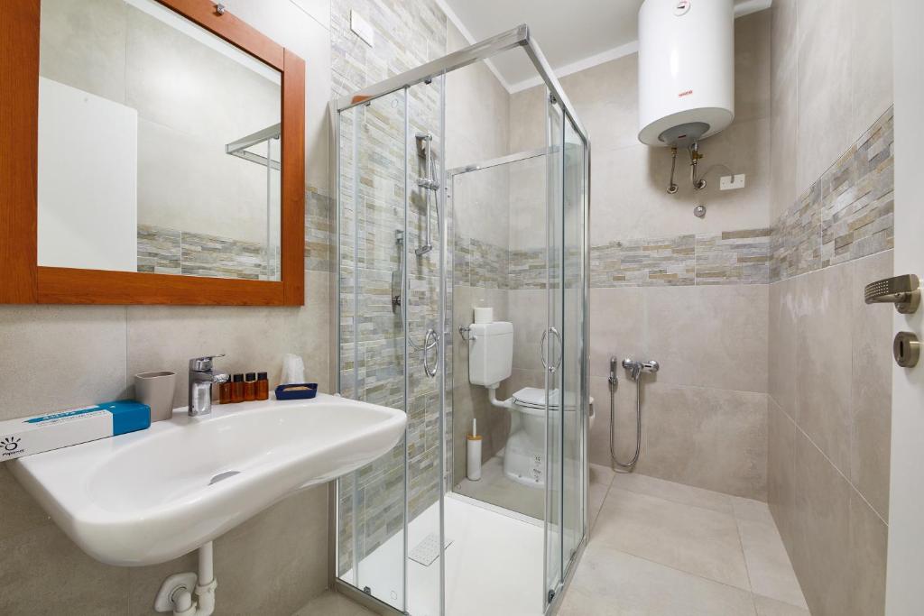 une salle de bain avec un lavabo et une douche en verre dans l'établissement Lilium Maris Hotel, à Bibione 56 autres photos