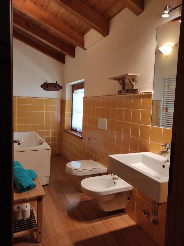 La salle de bains est pourvue de 2 toilettes, d'un lavabo et d'une baignoire. dans l'établissement Villa Betulla con piscina privata sul lago di Como, à Colico