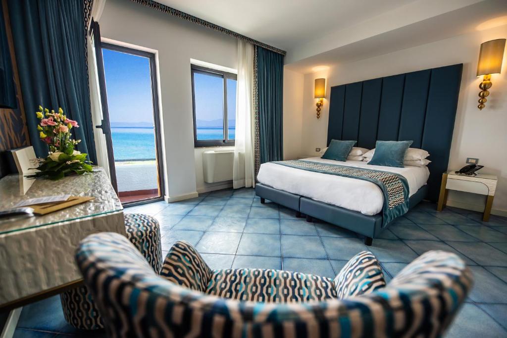 une chambre d'hôtel avec un lit et deux chaises dans l'établissement Hotel Oasi Di Kufra, à Sabaudia