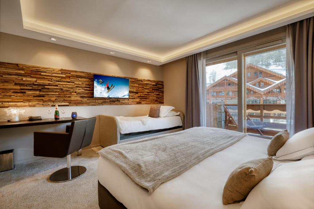 une chambre d'hôtel avec deux lits et un bureau dans l'établissement Hotel Le Tremplin, à Méribel