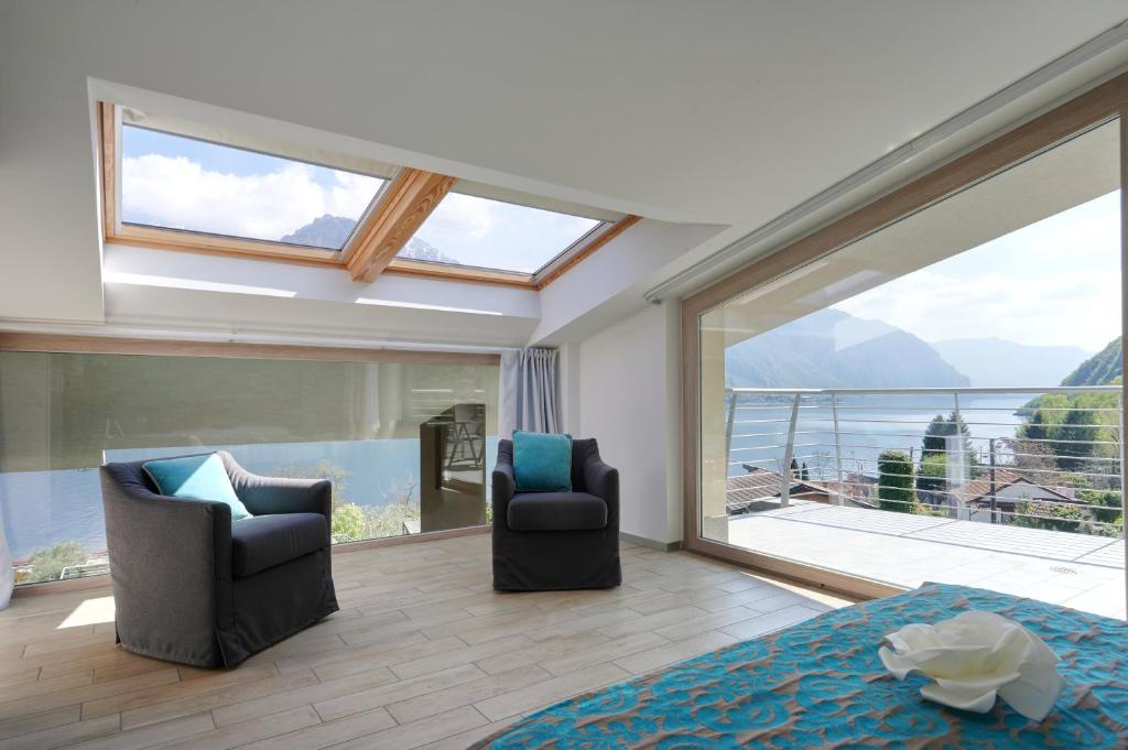 une chambre avec deux chaises et un lit et une grande fenêtre dans l'établissement Bellagio Village - Holiday Apartments by the Lake - Seasonal Warm Pool and Sauna, à Oliveto Lario