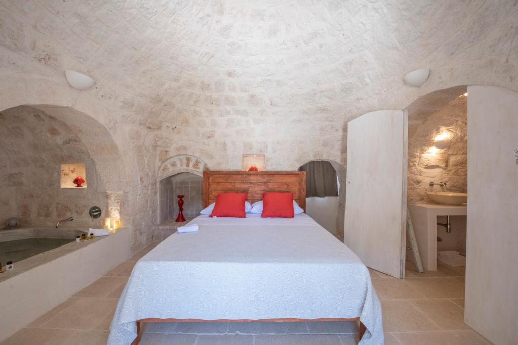 - une chambre avec un lit doté d'oreillers rouges et d'une baignoire dans l'établissement Tenuta Trullo Pietra Bianca, à Ostuni