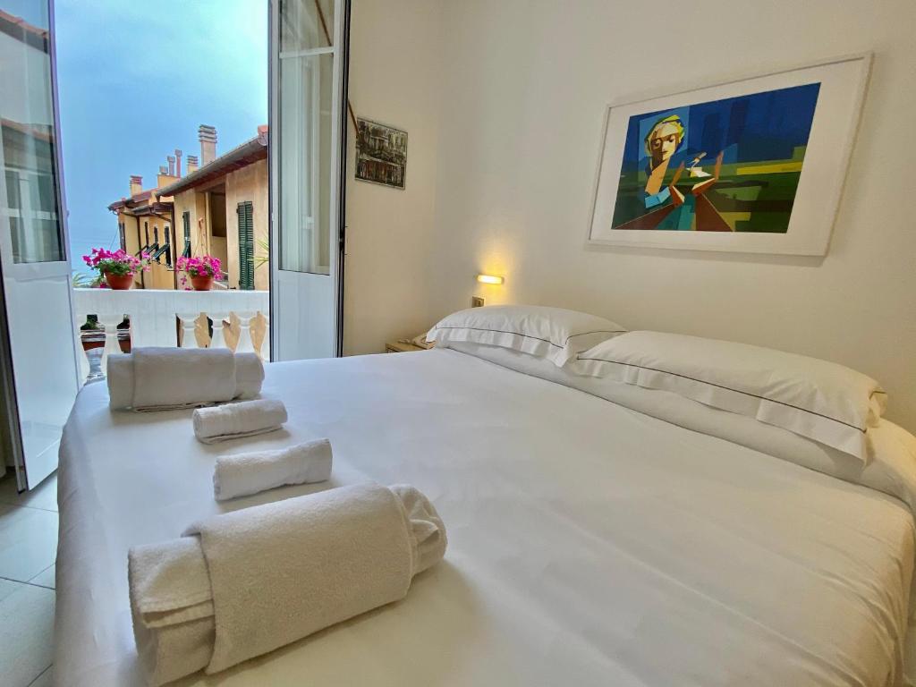 un grand lit blanc dans une chambre avec une fenêtre dans l'établissement Hotel Alba Chiara, à Finale Ligure