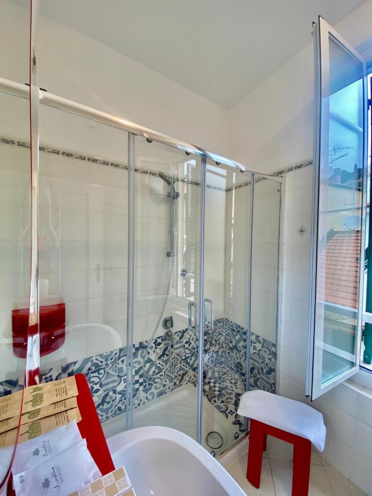 La salle de bains est pourvue d'une douche avec un tabouret rouge. dans l'établissement Hotel Alba Chiara, à Finale Ligure