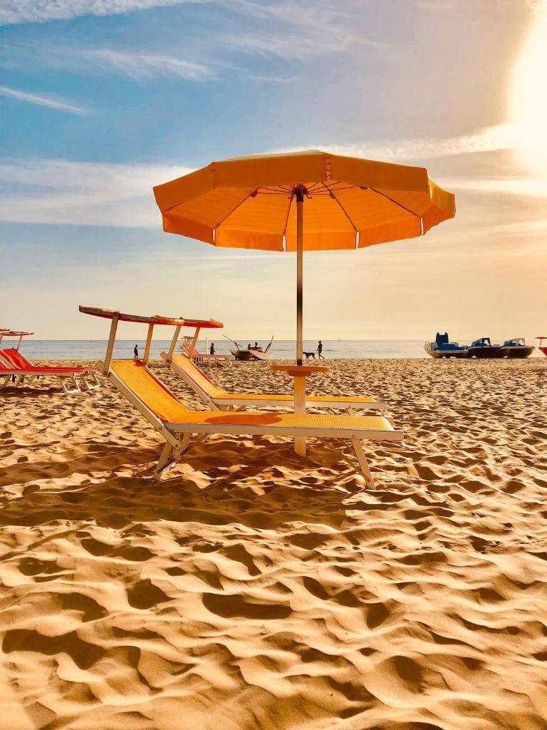 - une plage de sable avec un parasol et des chaises dans l'établissement Hotel Villa Lieta, à Rimini
