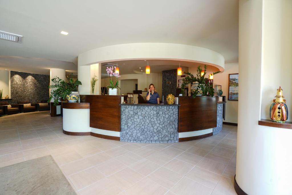 une femme assise au comptoir d'un hall d'hôtel dans l'établissement Hotel Residence Sciaron, à Capo Vaticano 57 autres photos