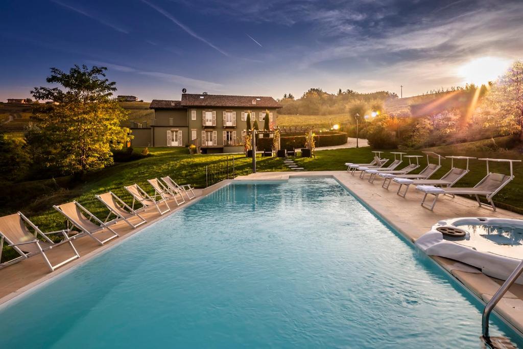 une piscine avec des chaises longues et une maison dans l'établissement Casale Dell'acero Rosso 10, Emma Villas, à Canelli