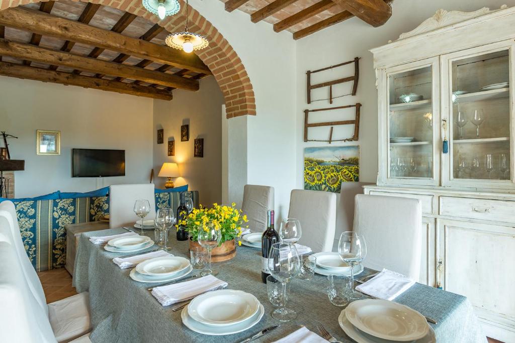 une salle à manger avec une table avec des assiettes et des verres à vin dans l'établissement CASALE MONTEGIOVI 6, Emma Villas, à Montegiovi
