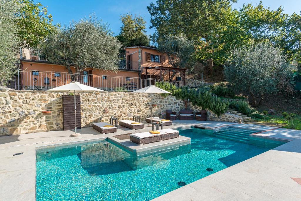 une piscine avec des chaises et un mur en pierre dans l'établissement CASALE MONTEGIOVI 6, Emma Villas, à Montegiovi