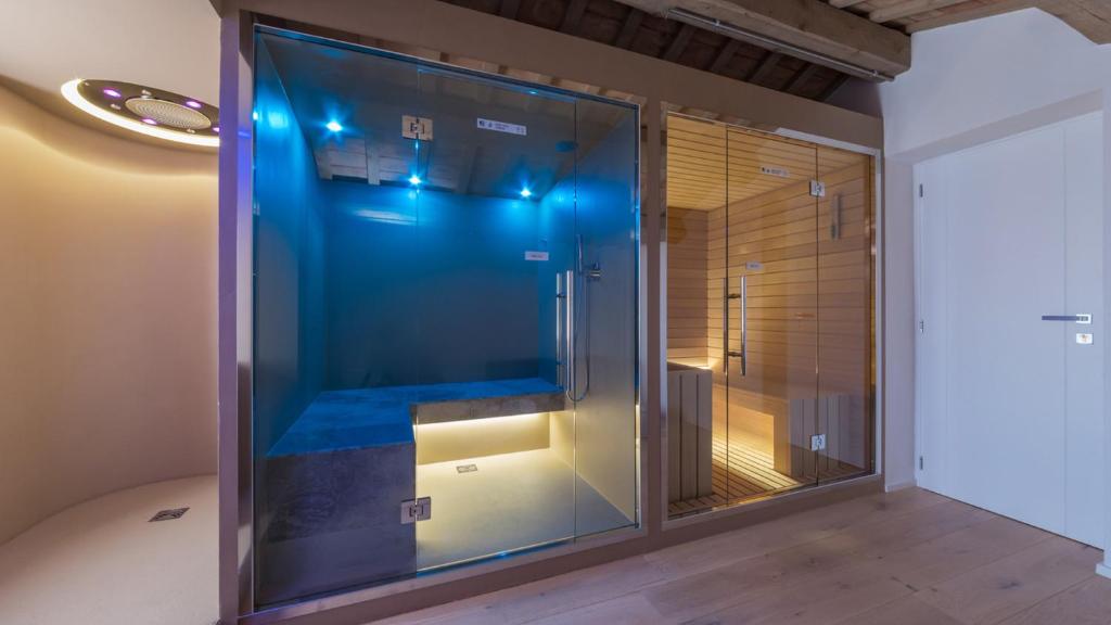 - une douche en verre avec des lumières bleues dans la chambre dans l'établissement Dimora Montefiore 11, Emma Villas, à Montefiore dellʼAso