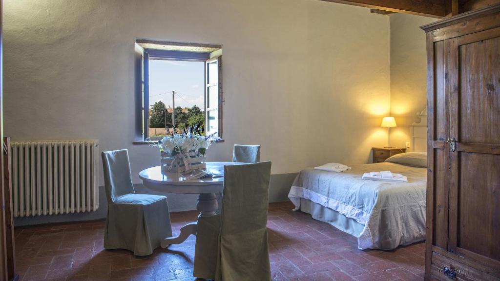 Cette chambre comprend une table, un lit et une fenêtre. dans l'établissement Le Caselle 26, Emma Villas, à Cortone 62 autres photos
