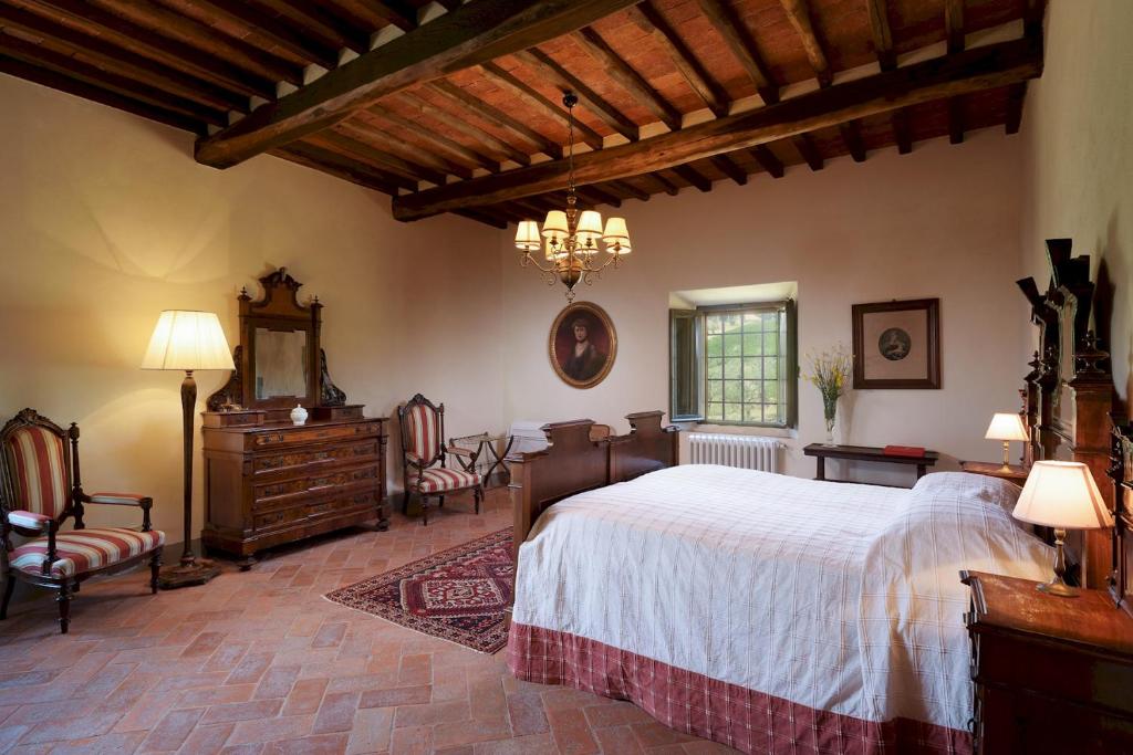 une chambre avec un grand lit et un lustre dans l'établissement Marangole 12, Emma Villas, à Radda in Chianti