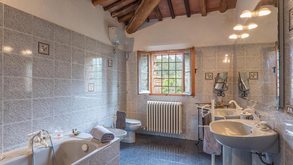 une salle de bain avec deux lavabos et une baignoire et des toilettes dans l'établissement PODERINO 6, Emma Villas, à Trequanda